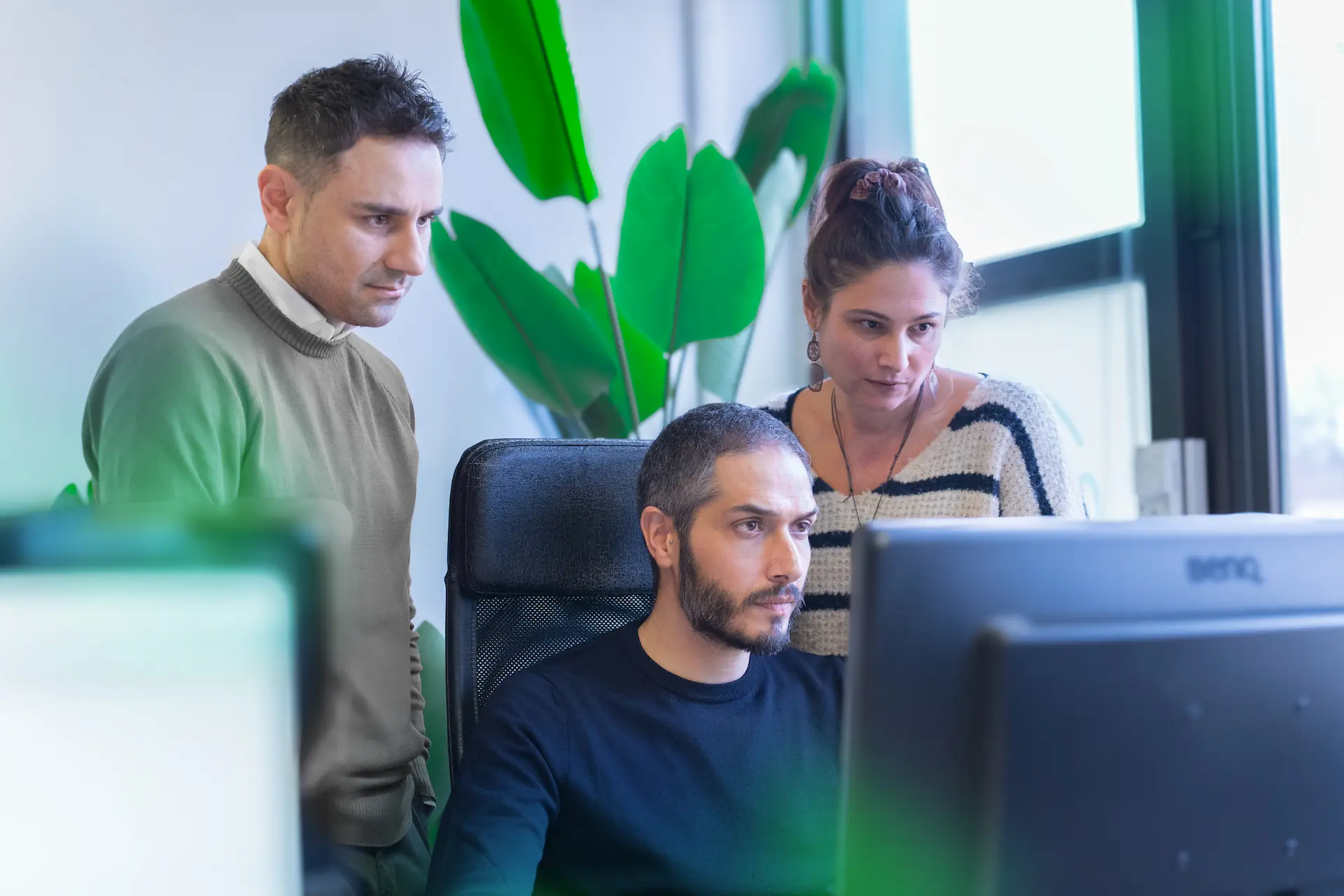 Tre collaboratori di Winet concentrati davanti a un monitor, impegnati nello sviluppo di un progetto di Business Process Management (BPM) per Banco BPM.